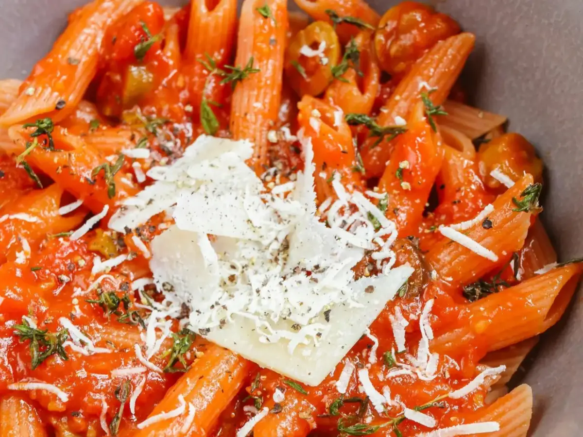 Penne w sosie pomidorowym z oliwkami i parmezanem, aromatyczne dania z makaronem.