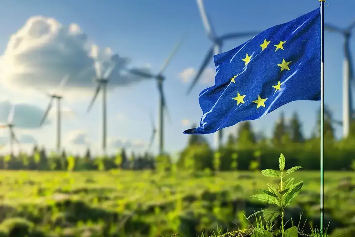 Flaga UE powiewa nad farmą wiatrową, symbolizując, czego dotyczy zielony ład: zrównoważony rozwój i czystą energię dla przyszłości.