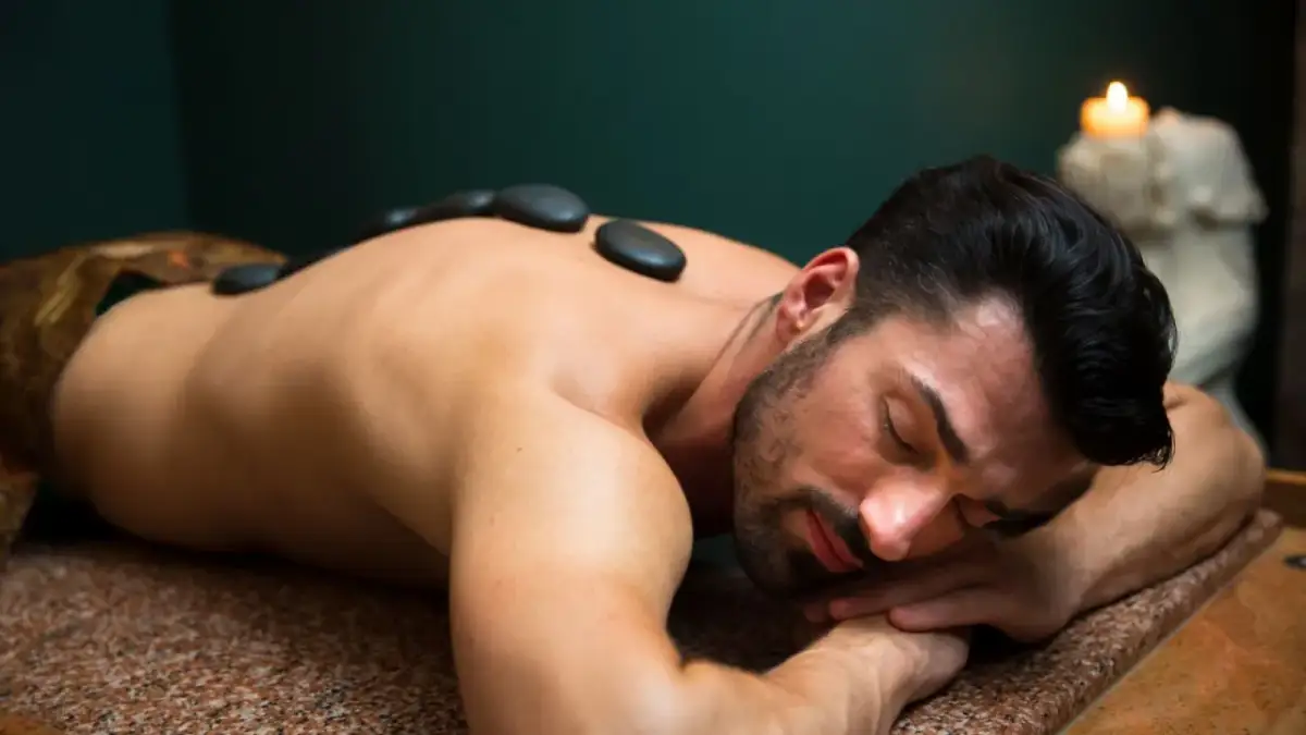 Mężczyzna relaksuje się podczas masażu gorącymi kamieniami. To idealny **spa dla mężczyzn**, gdzie można odprężyć ciało i umysł.