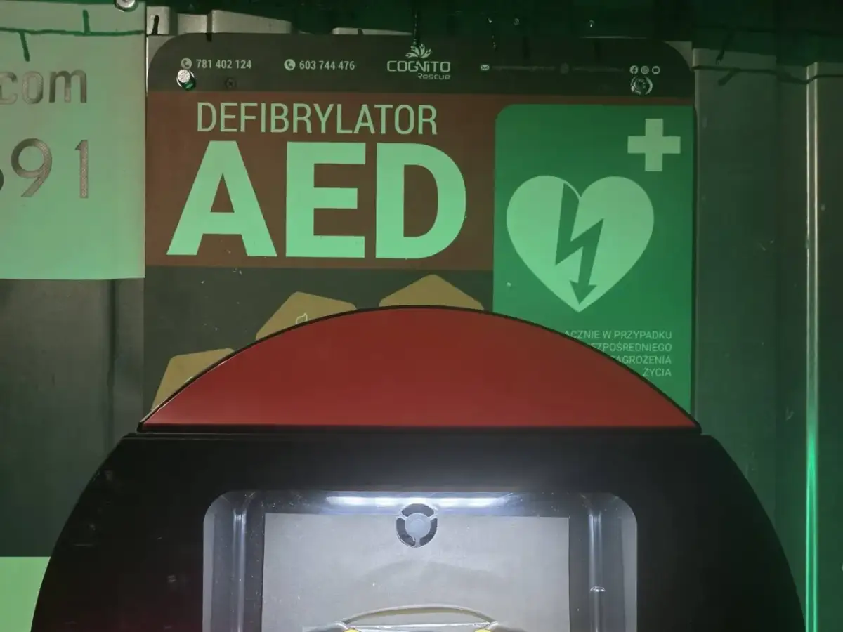 Defibrylator AED z zielonym symbolem serca i błyskawicy.