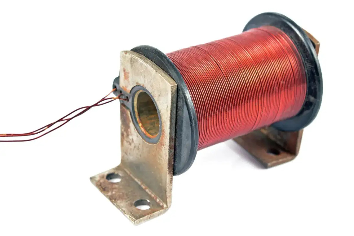 Cewka z miedzianym uzwojeniem, na metalowym mocowaniu. Prąd indukcyjny powstaje w uzwojeniu na skutek zmian pola magnetycznego.