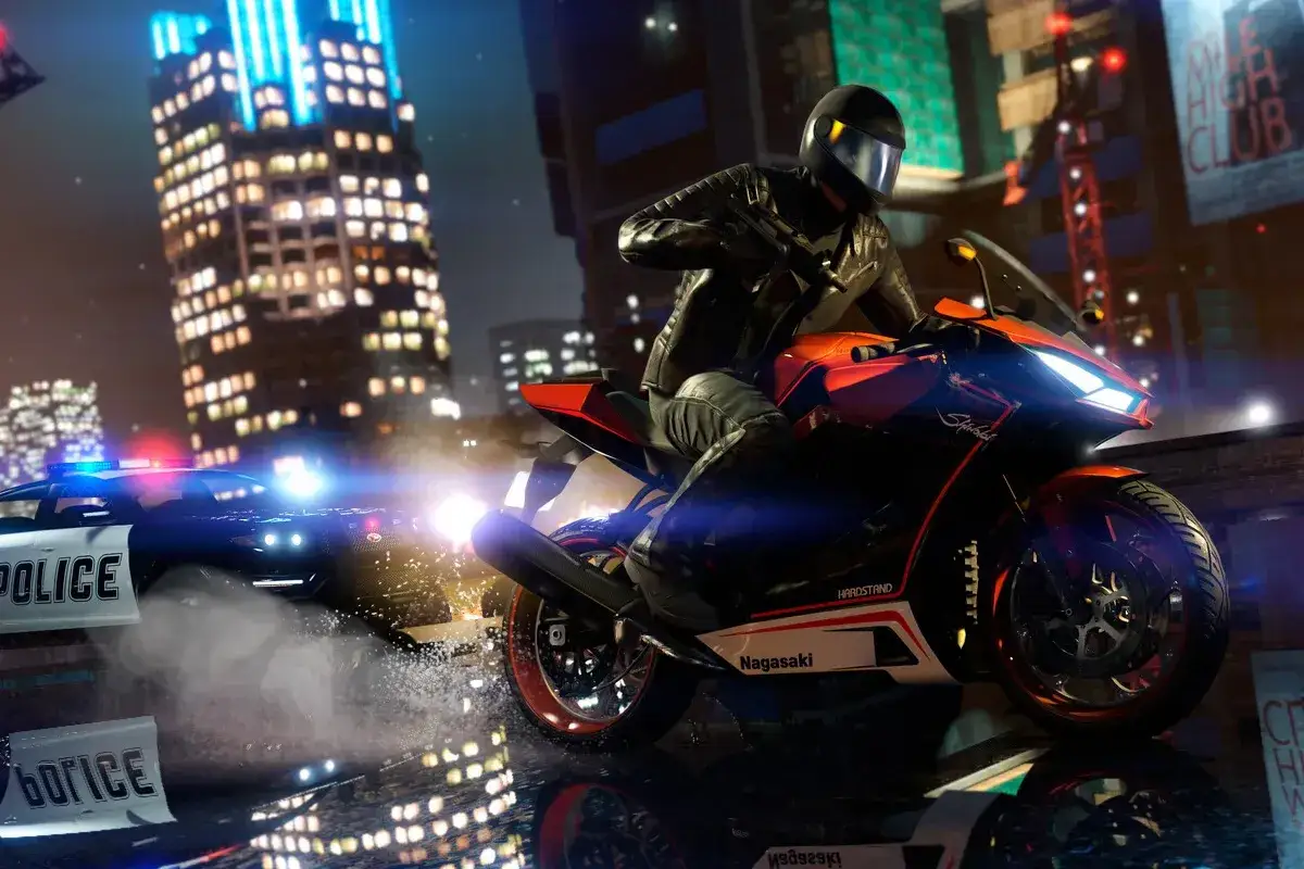 Motocyklista w kasku ucieka przed radiowozem policyjnym w nocnym mieście.