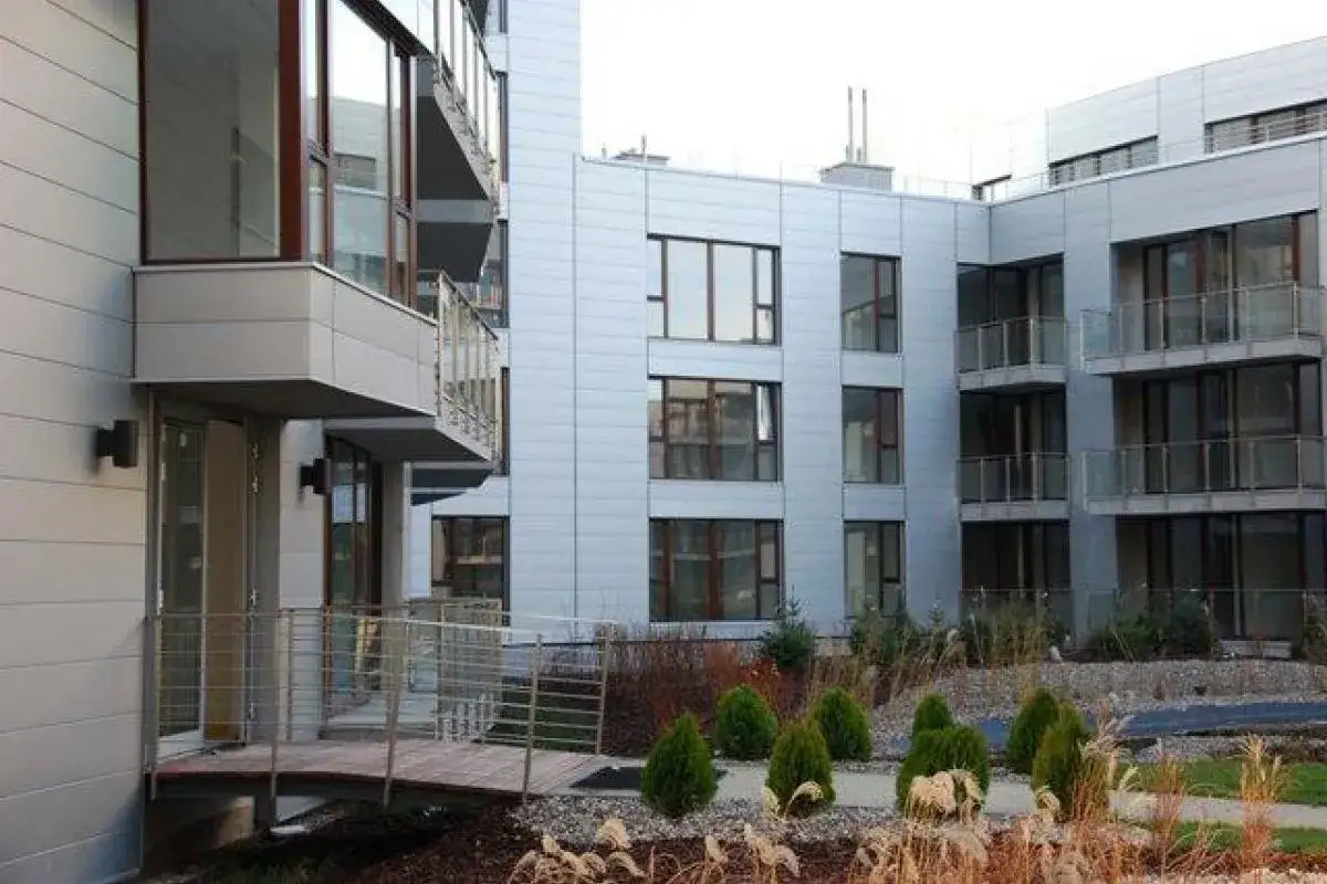Nowoczesne budynki mieszkalne Triton Park Apartments z balkonami i dużymi oknami, otoczone zadbaną zielenią.