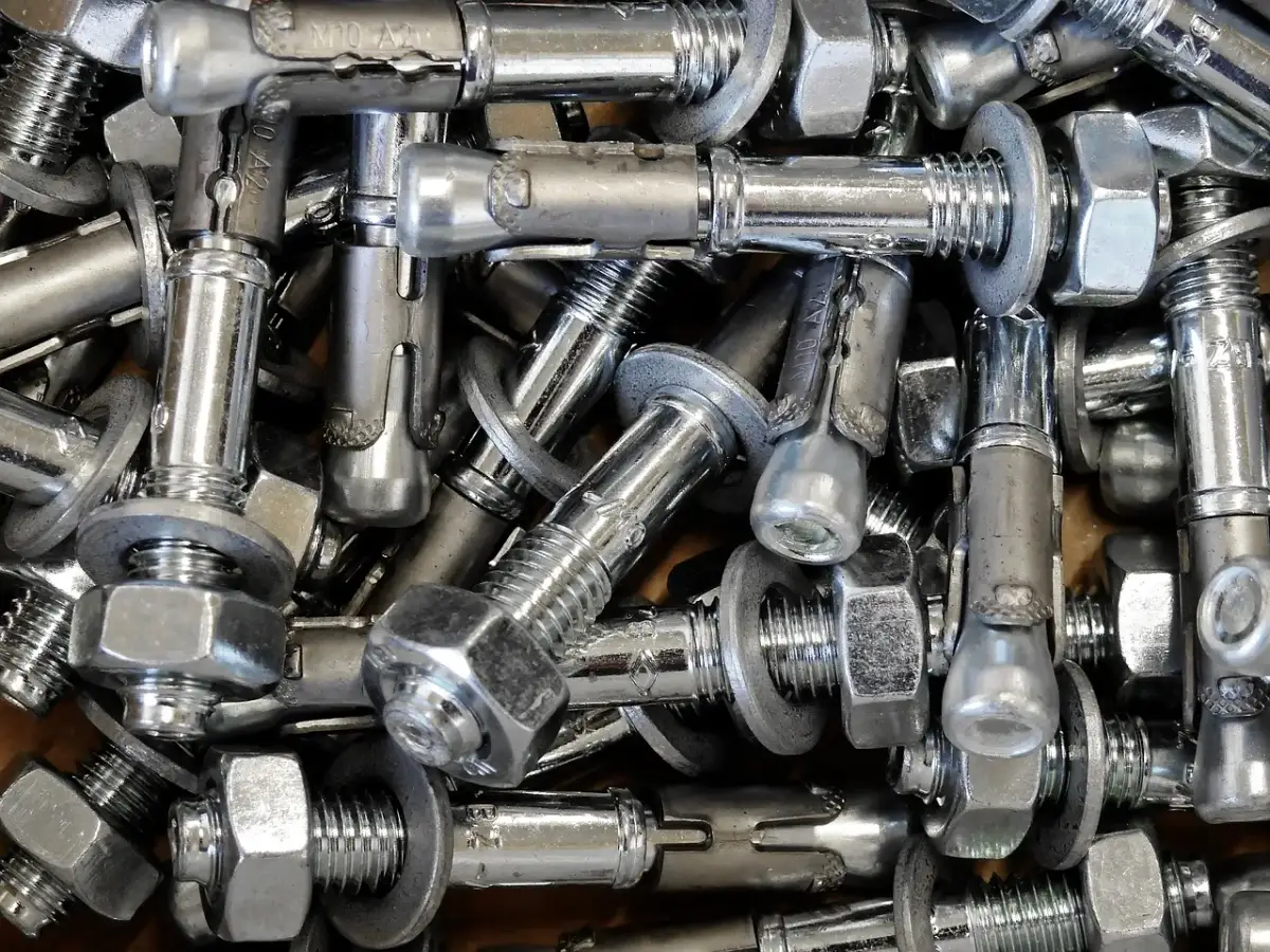 Zbliżenie na metalowe kotwy chemiczne z nakrętkami i podkładkami.