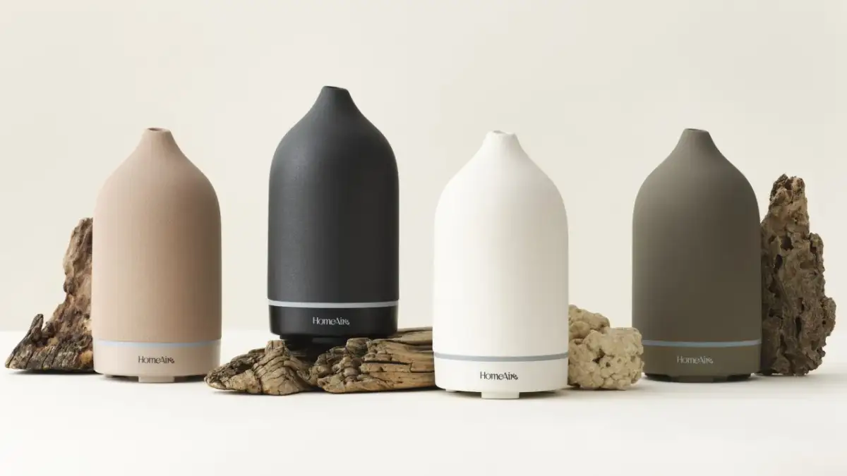 Cztery dyfuzory HomeAir w różnych kolorach, otoczone naturalnymi elementami. Idealne do inhalacji, np. z olejkiem eukaliptusowym.