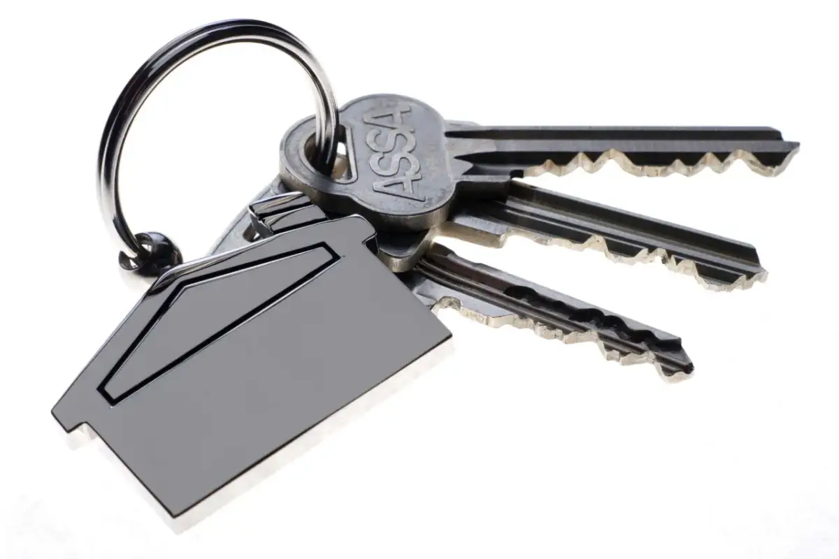 Pęk kluczy z breloczkiem w kształcie domu. Różne rodzaje kluczy do drzwi, jeden z napisem ASSA.