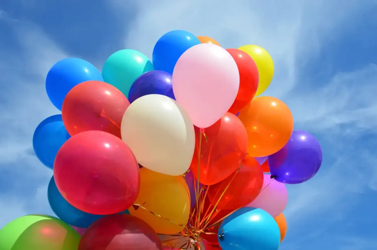 Kolorowe balony unoszą się na błękitnym niebie. Czy zwykłe balony można nadmuchać helem? Tak, jeśli są odpowiednio przygotowane.