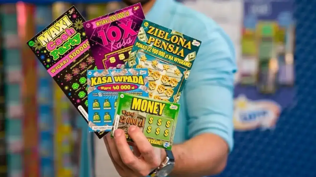 Dłoń trzyma kilka zdrapek Lotto z różnymi nazwami i kwotami wygranych.