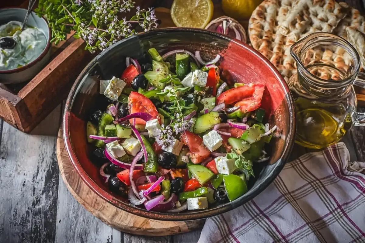 Frischer griechischer Salat mit Feta, Tomaten, Gurken, Oliven und Zwiebeln in einer Schüssel.