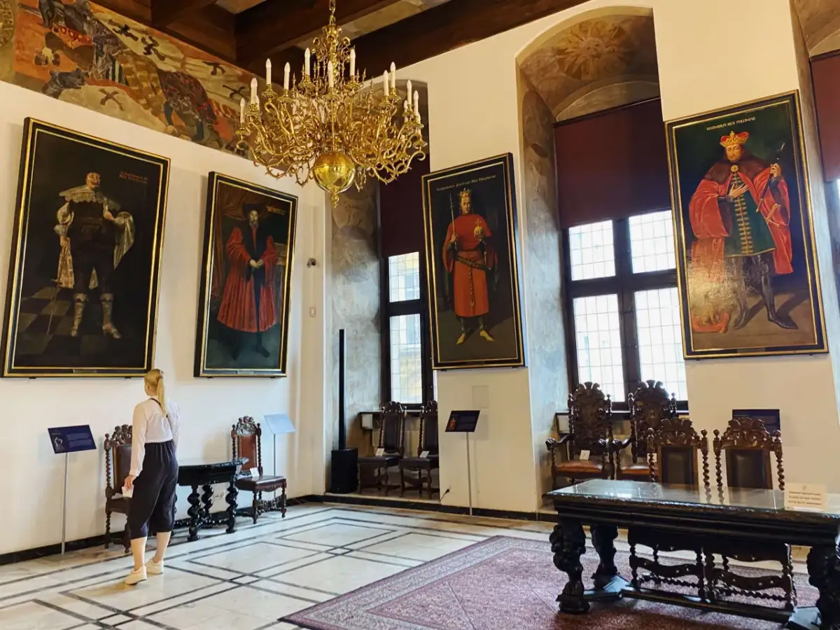Wielka sala z portretami królów i bogatym żyrandolem. Sprawdź muzeum narodowe w gdańsku godziny otwarcia, by zobaczyć to na żywo.