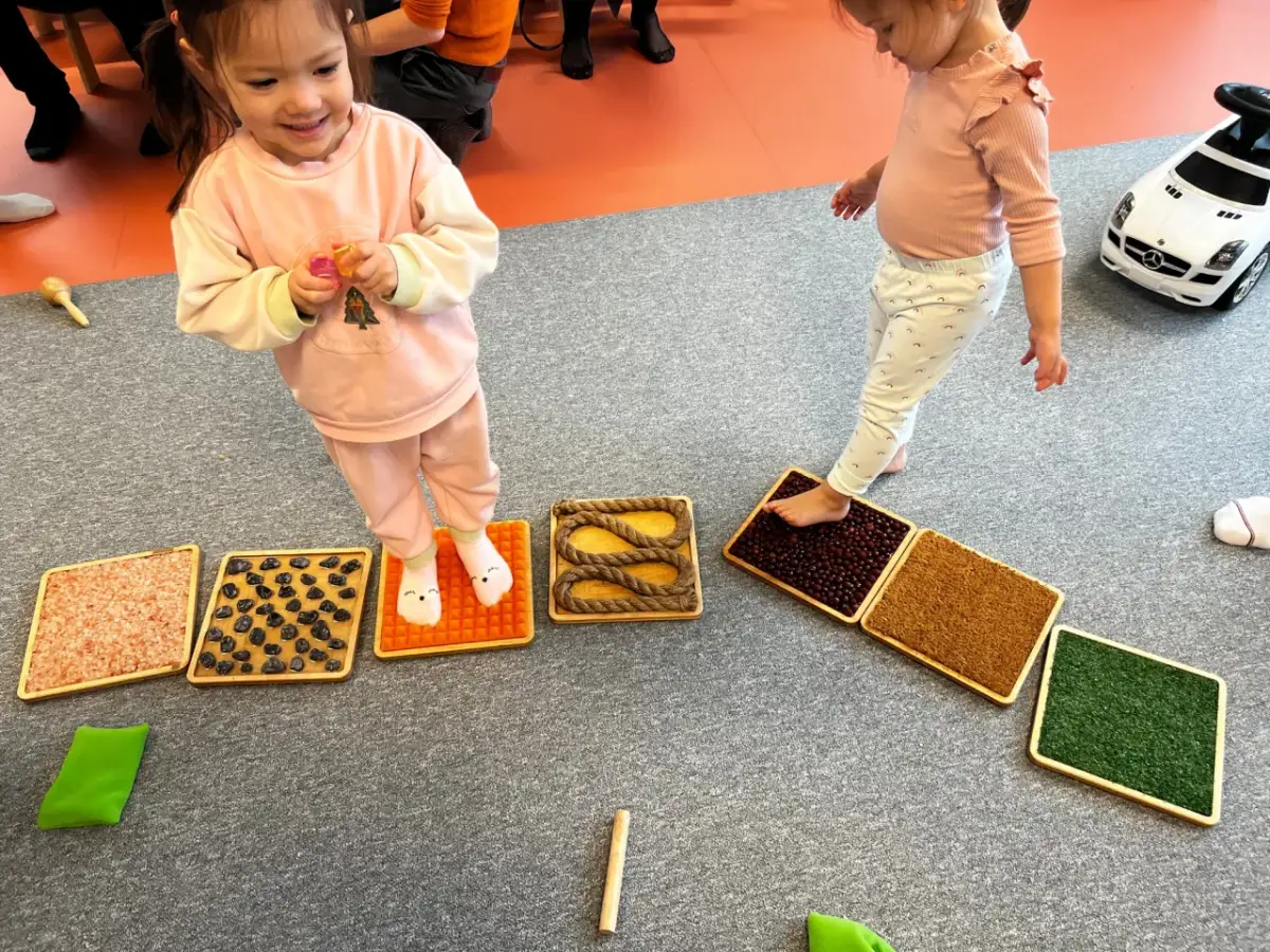 Dzieci stąpają po sensorycznych matach z różnymi fakturami, wspierając integrację sensoryczną.