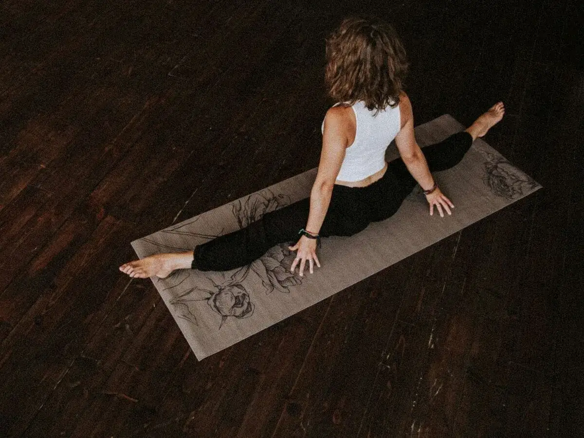 Kobieta na macie do ćwiczeń w szpagacie. Dobra mata do ćwiczeń to podstawa.