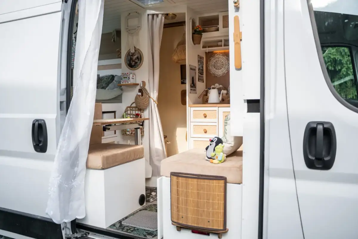 Przytulne wnętrze kampervana z wygodnymi siedzeniami, stolikiem i dekoracjami.