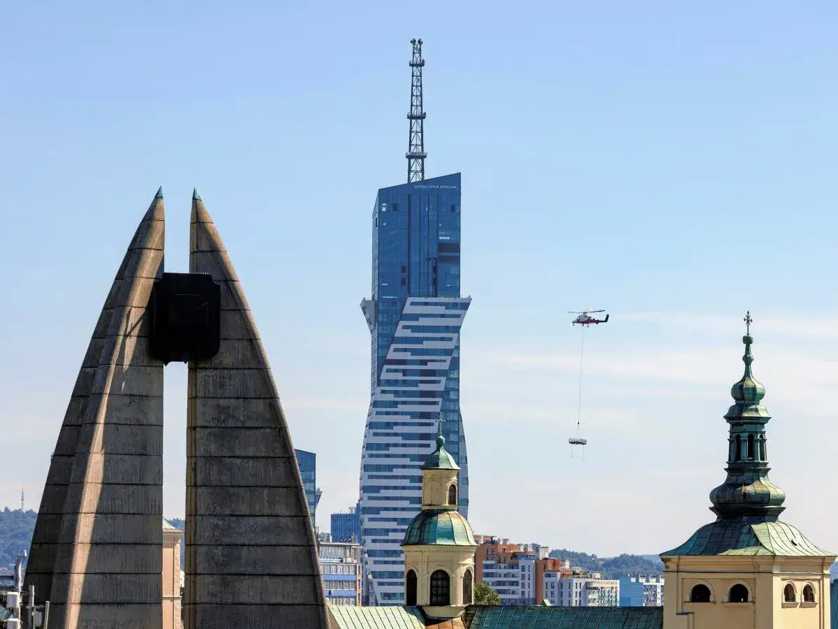Widok na najwyższy budynek mieszkalny w Polsce, z helikopterem dostarczającym ładunek.