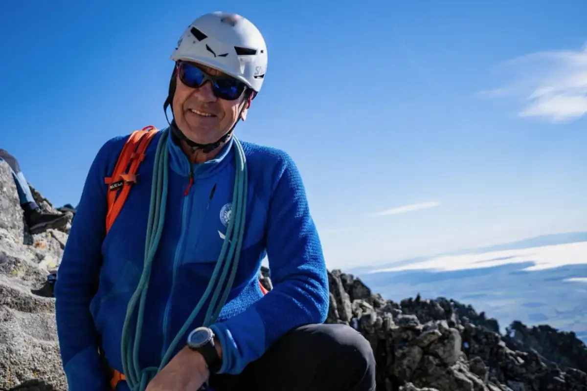 Uśmiechnięty alpinista w kasku i okularach przeciwsłonecznych, gotowy na wejście na Gerlach. Liny i plecak świadczą o jego pasji.