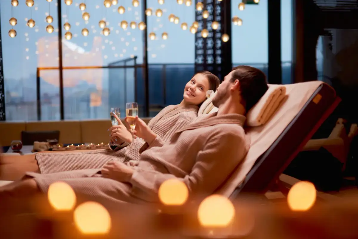 Para relaksująca w spa: para w szlafrokach z kieliszkami szampana, przy świecach.