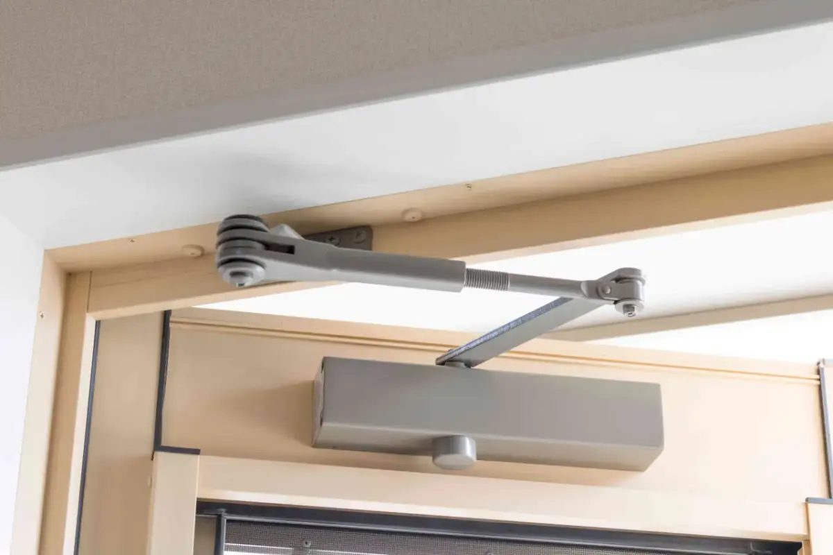 Mechanizm samozamykacza drzwi, zamontowany na futrynie, zapewnia płynną regulację domykania.