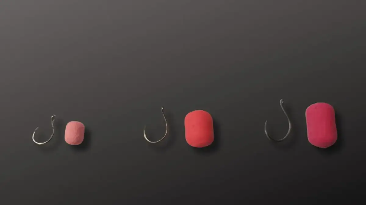 Trzy zestawy haczyków wędkarskich z przynętami w różnych rozmiarach na ciemnym tle.