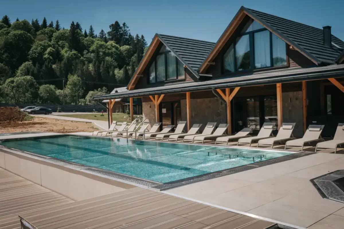 Nowoczesny bieszczady hotel z basenem i leżakami, otoczony zielonymi lasami. Idealne miejsce na relaks.