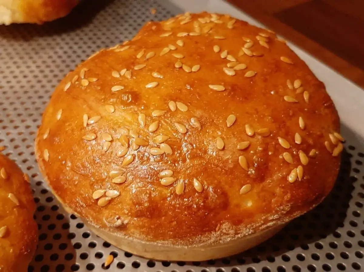 Un pain à burger maison doré et moelleux, parsemé de graines de sésame.