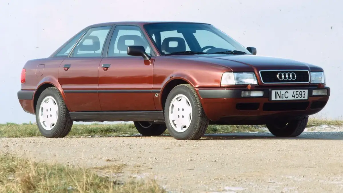 Roter Audi 80 B4 Limousine von vorne rechts auf Schotterweg.