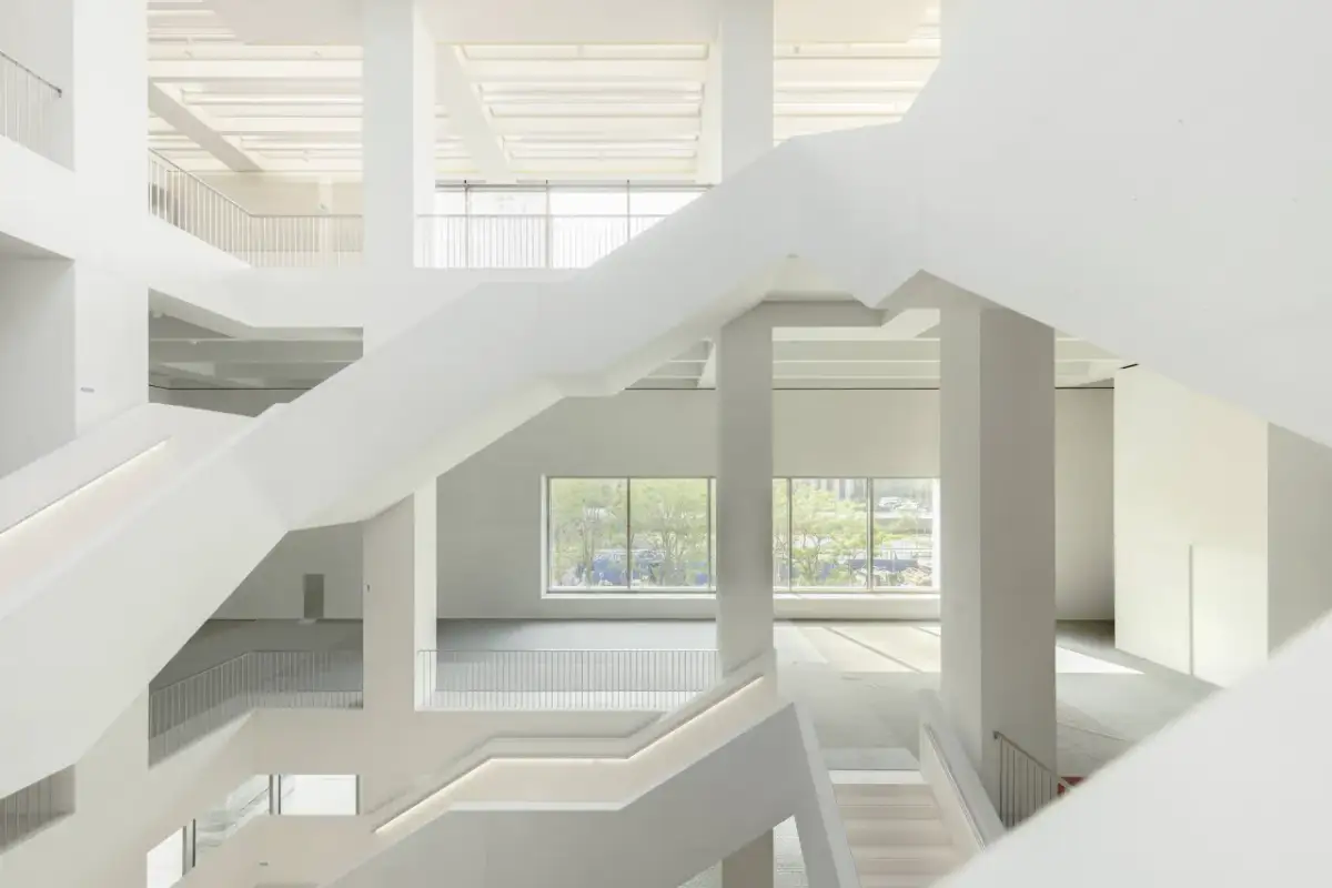 Wnętrze nowego muzeum sztuki nowoczesnej w Warszawie. Białe, geometryczne schody i przestrzenie tworzą nowoczesną architekturę.