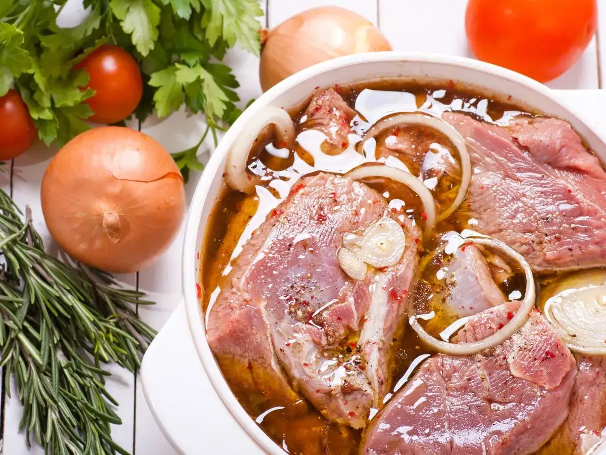 Kawałki indyka w aromatycznej marynacie z cebulą i ziołami, gotowe do pieczenia.