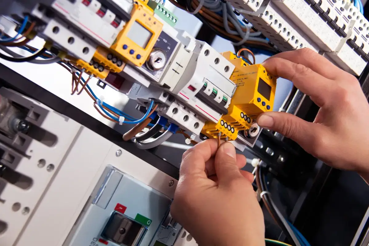 Elektryk podłącza przewody do żółtego modułu w skrzynce rozdzielczej. To część prac związanych z pge cesja umowy.