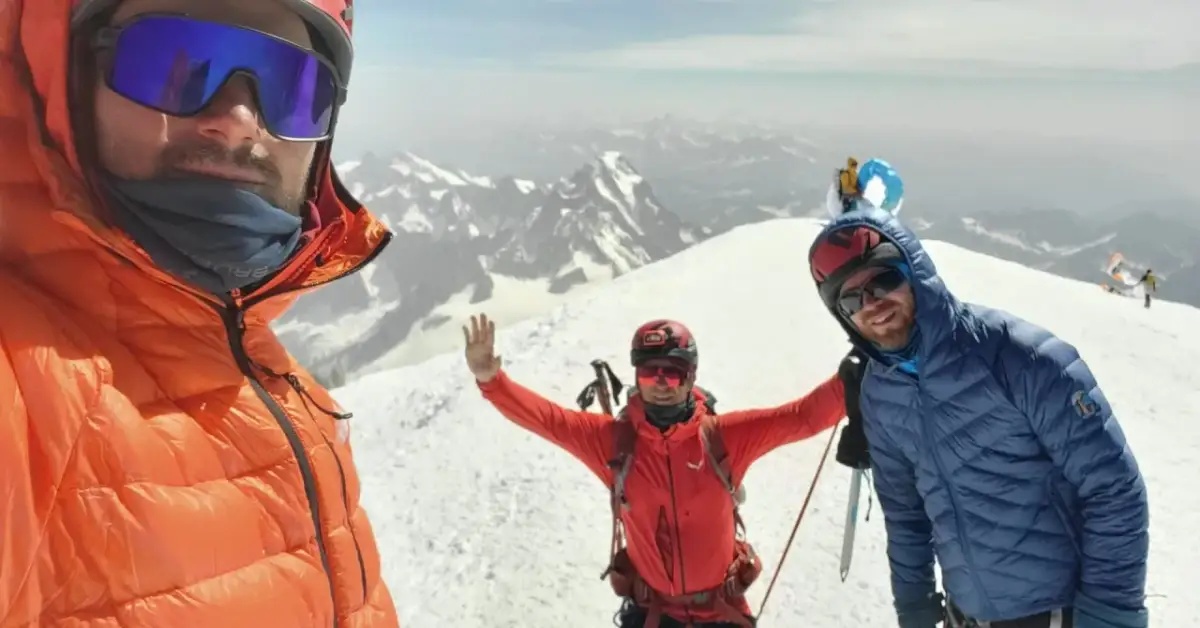 Trzech alpinistów na szczycie Mont Blanc cieszy się widokiem.