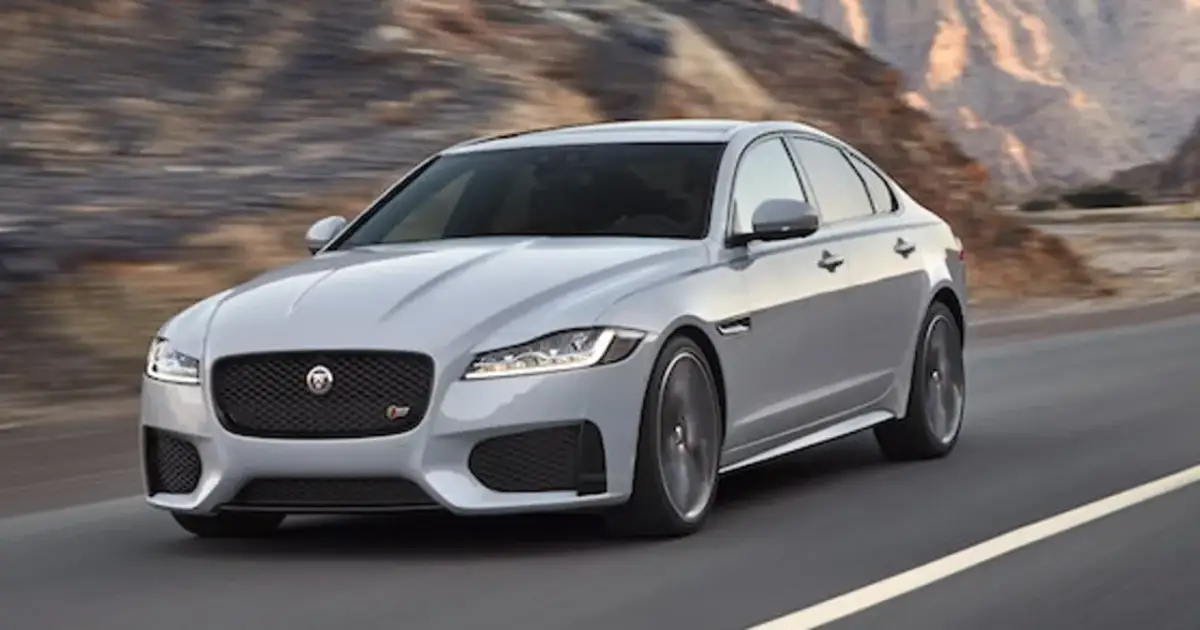 Srebrny Jaguar XF pędzi po pustynnej drodze. Czy jaguar xf jest drogi w utrzymaniu? To pytanie zadaje sobie wielu miłośników tej marki.
