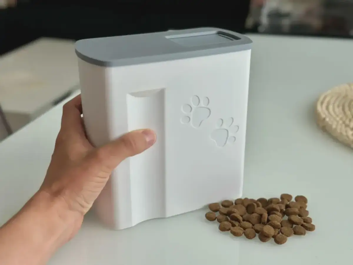 Biały dozownik suchej karmy dla psa z łapkami, obok rozsypana karma. Prosty sposób, jak zrobić dozownik suchej karmy dla psa.