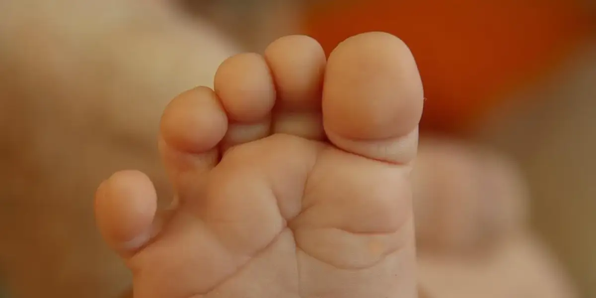 Zbliżenie na małą, dziecięcą stopę z widocznymi palcami i fałdkami skóry.