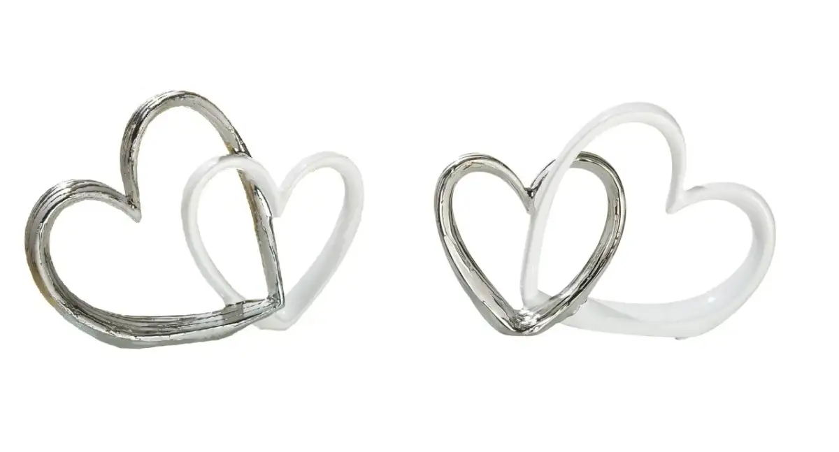Zwei ineinander verschlungene Herzskulpturen, eine silberfarben, die andere weiß.