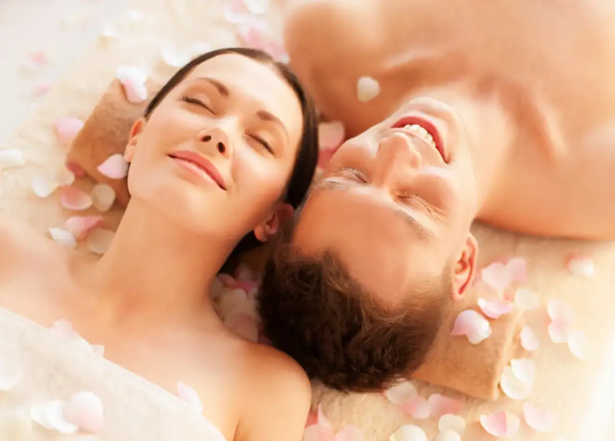 Para spędza relaksujący dzień w spa, leżąc wśród płatków róż.