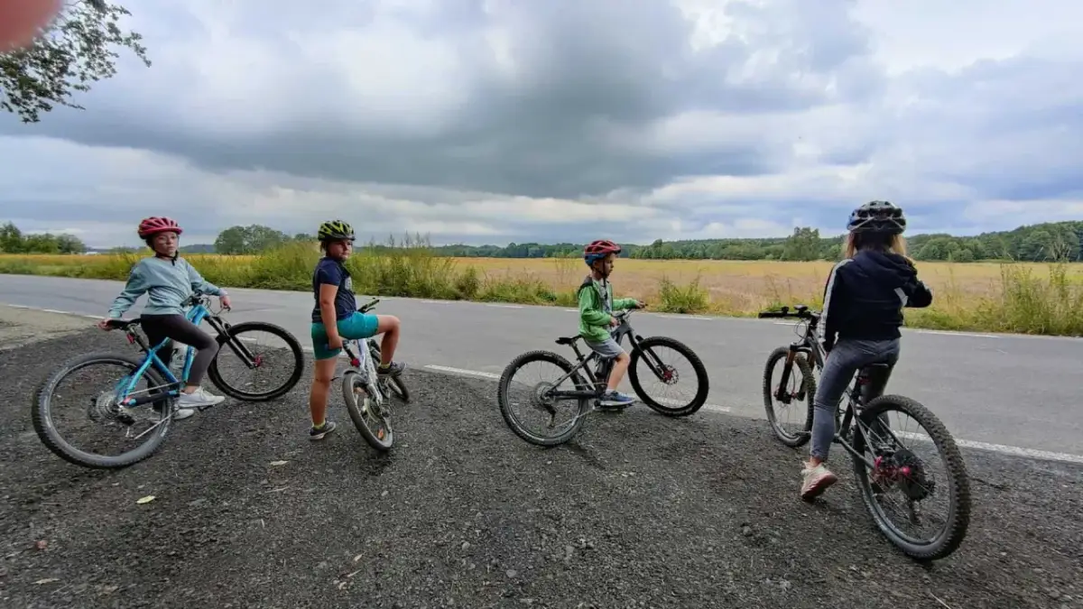 Dzieci na rowerach, szukają idealnego roweru na 140 cm wzrostu. Na tle pól i chmur.
