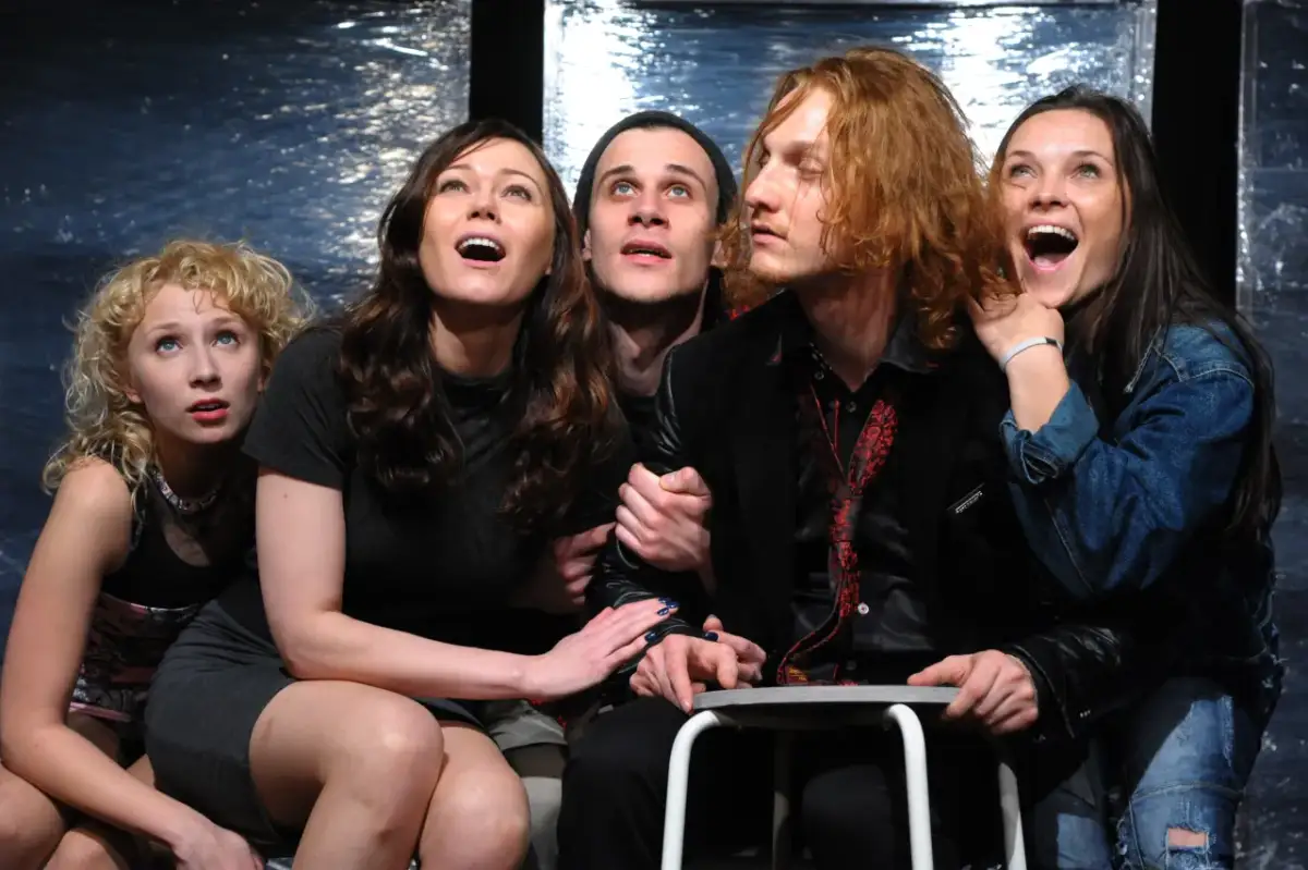 Młodzi aktorzy z "Dzieci z dworca Zoo" spektakl, zapatrzeni w górę, przeżywają emocje na scenie.