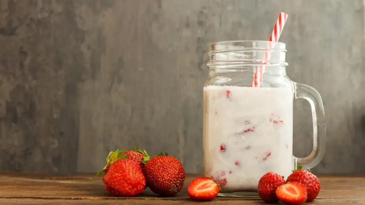 Kefir z truskawkami w słoiku, obok świeże owoce. Niska wartość indeksu glikemicznego sprawia, że to zdrowa przekąska.