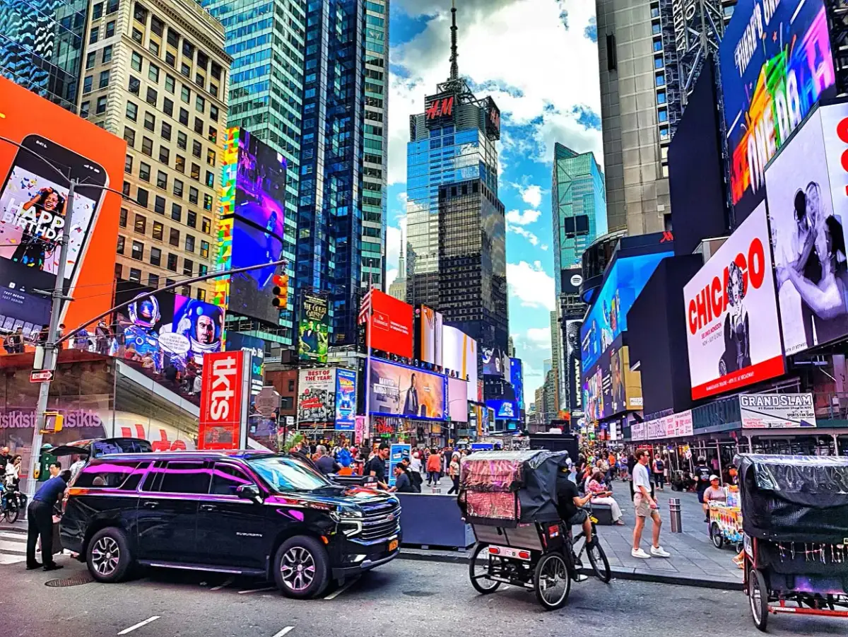 Times Square w Nowym Jorku z neonami, ludźmi i rikszami.