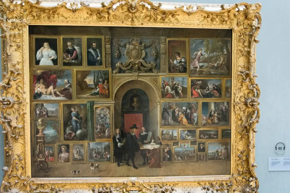 Obraz w złotej ramie, przedstawiający galerię obrazów w królewskich muzeach sztuk pięknych. W centrum grupa ludzi przy stole.