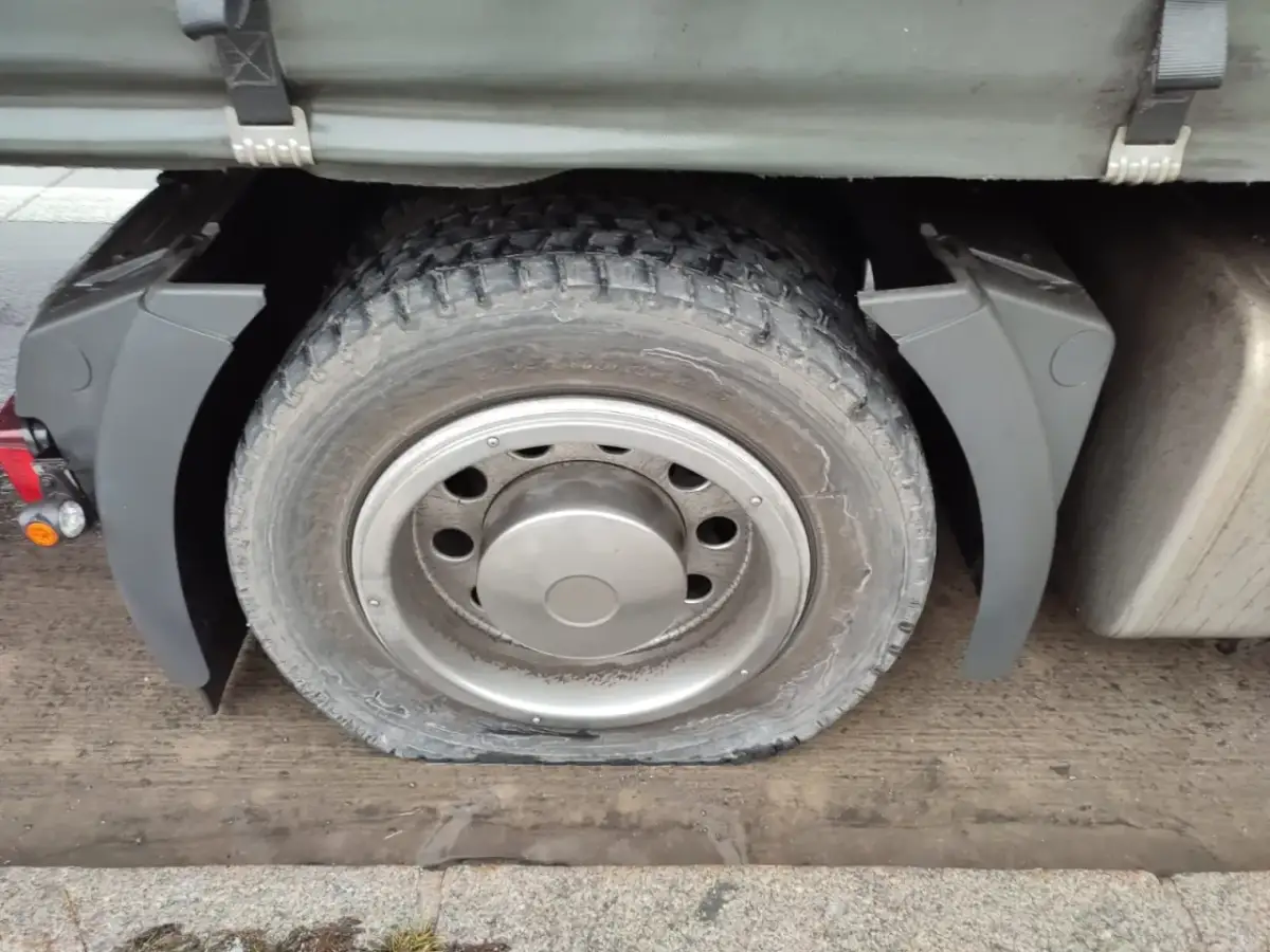 Płaska opona ciężarówki pod błotnikiem.