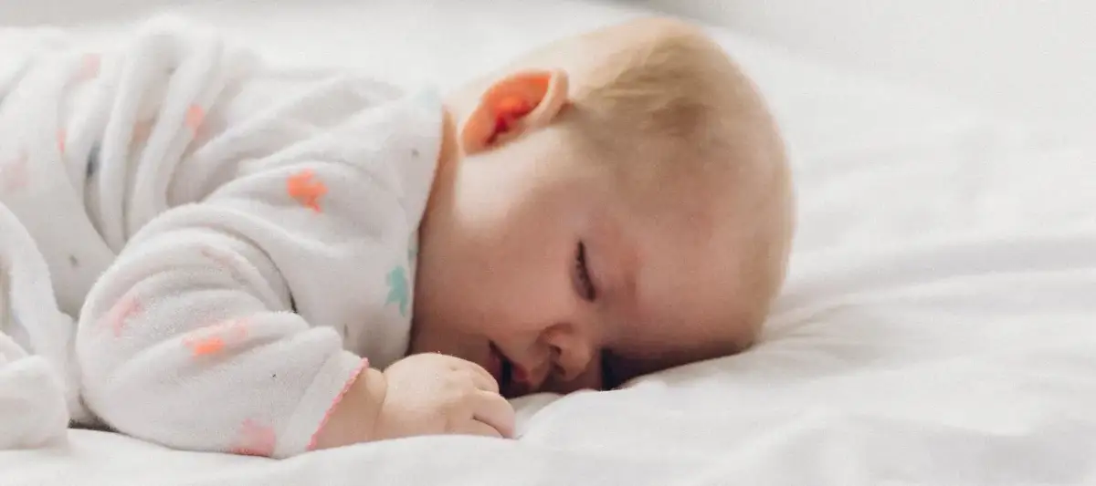 Śpiące dziecko w piżamce z kolorowymi wzorami. Czy dziecko powinno spać z rodzicami? Ta słodka drzemka może być odpowiedzią.