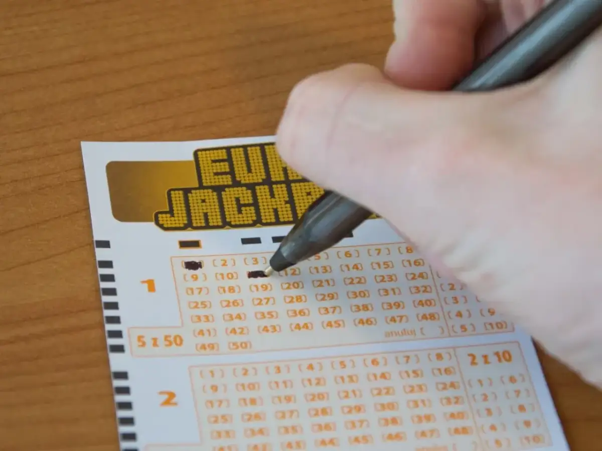 Dłoń zaznacza liczby na kuponie Eurojackpot. Zastanawiasz się, jak skreślić Eurojackpot? To proste!