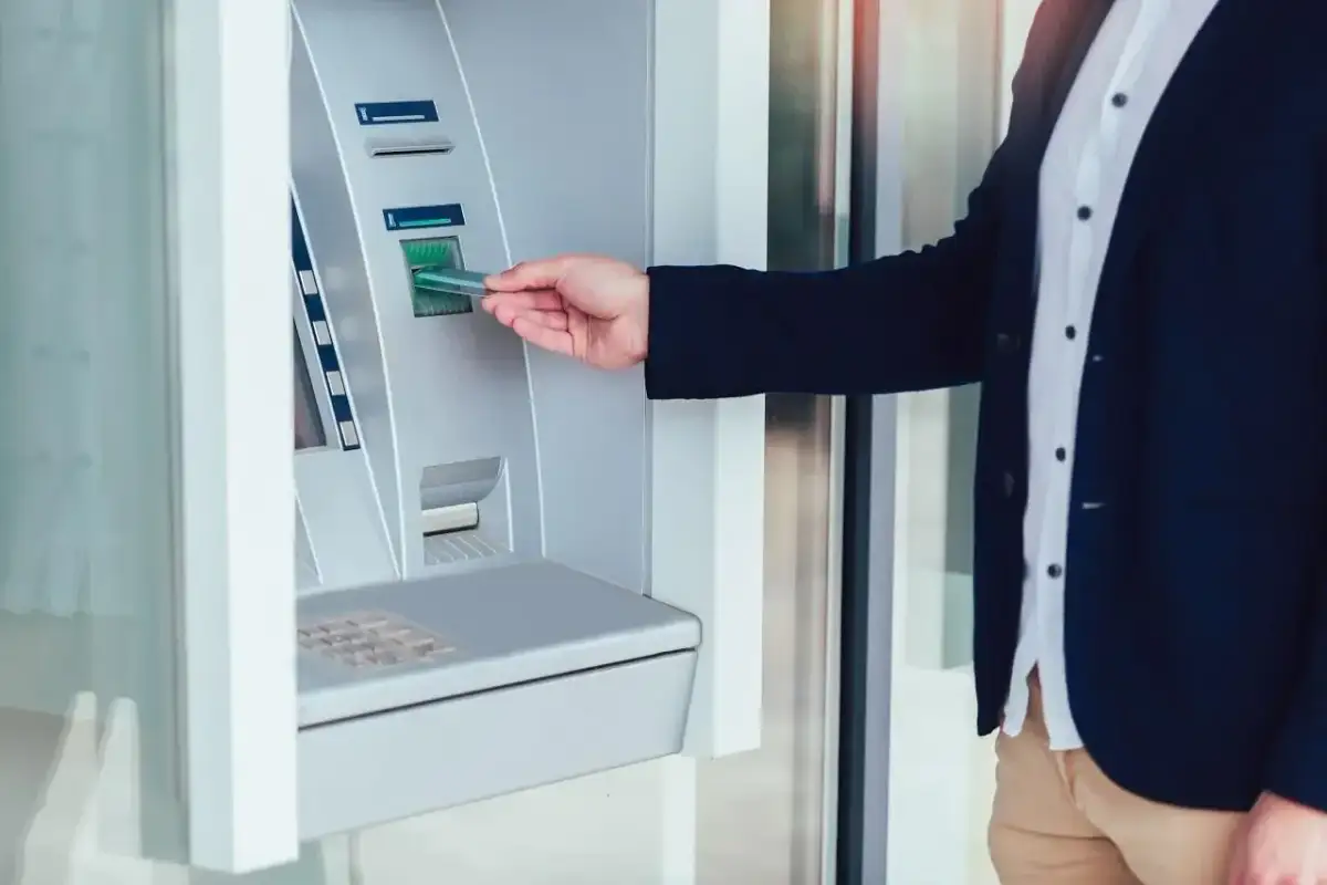 Mężczyzna w garniturze wkłada kartę do wpłatomatu euro. Szybka transakcja w bankomacie.