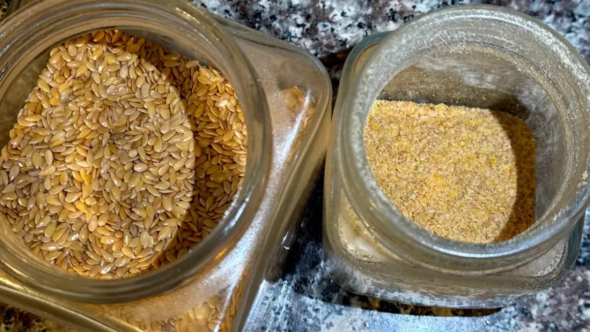 Dwa słoiki: jeden z całymi nasionami lnu, drugi z mielonym siemieniem lnianym, gotowym do przygotowania napoju.