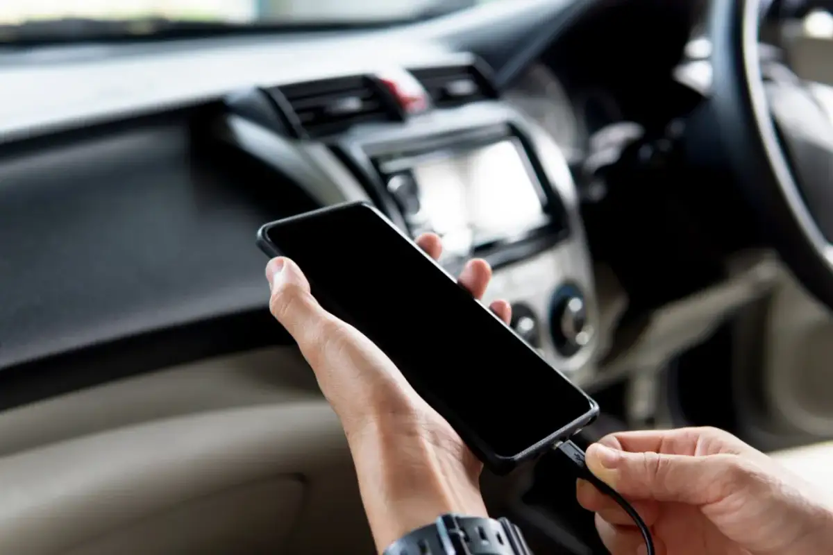 Ręce podłączają telefon do radia samochodowego, aby dołożenie bluetooth do radia samochodowego było proste.