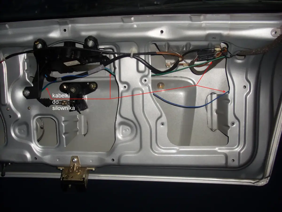 Wnętrze drzwi samochodu z widocznym siłownikiem centralnego zamka i okablowaniem.