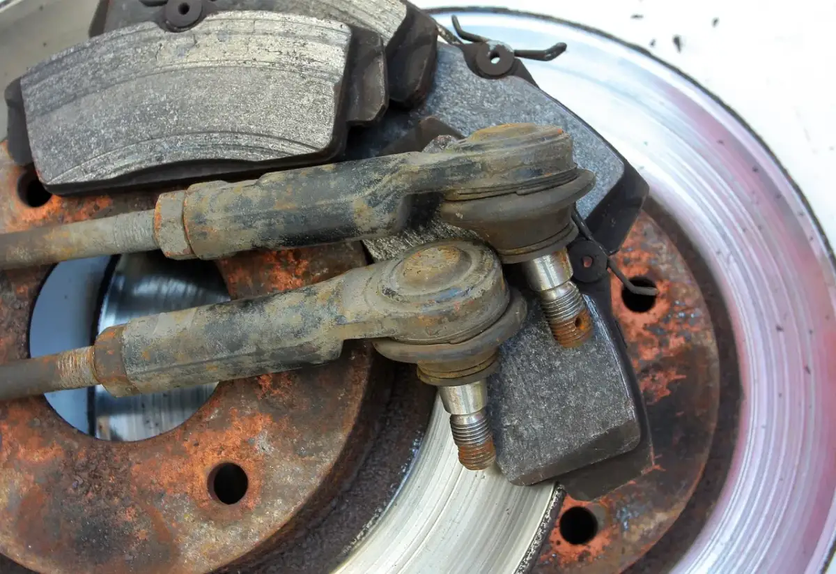 Zużyte drążki kierownicze i klocki hamulcowe czekają na wymianę. Rdza na tarczach hamulcowych sugeruje, że czas na serwis.