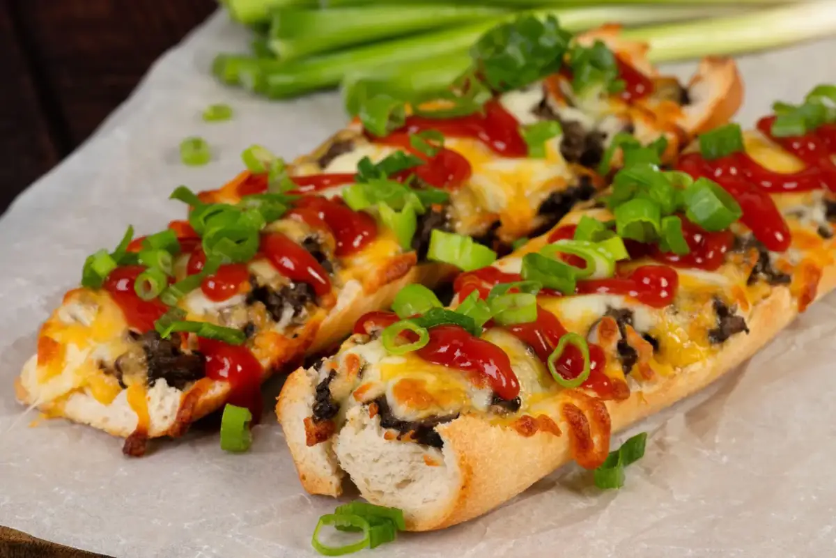 Pyszne zapiekanki z bagietki z serem, keczupem i szczypiorkiem. Idealne na szybką przekąskę.