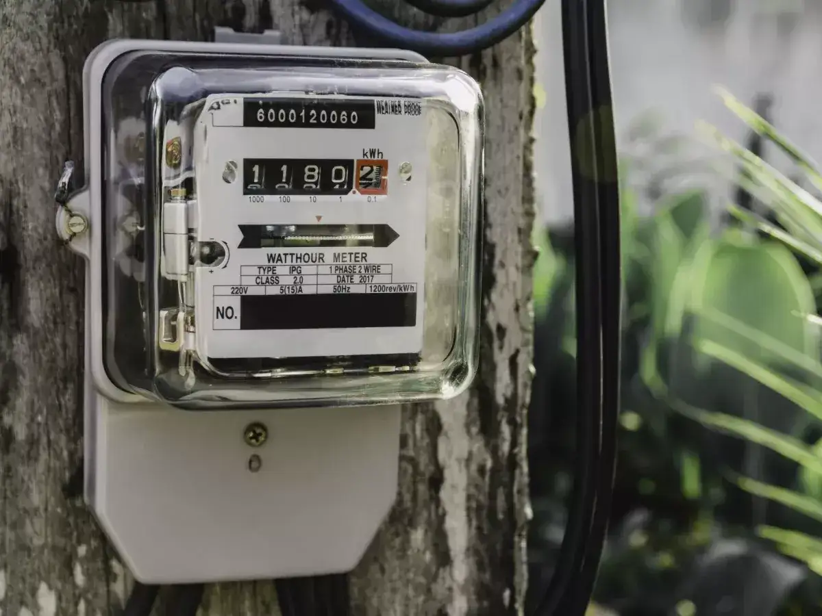 Podłączenie licznika prądu do drewnianego słupa. Urządzenie pokazuje zużycie energii elektrycznej.