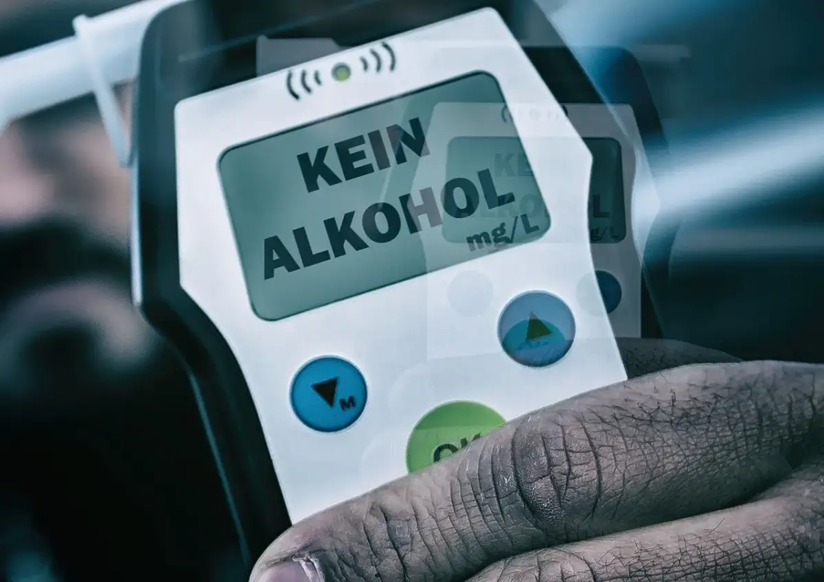 Dłoń trzyma alkomat z napisem "KEIN ALKOHOL" na wyświetlaczu.